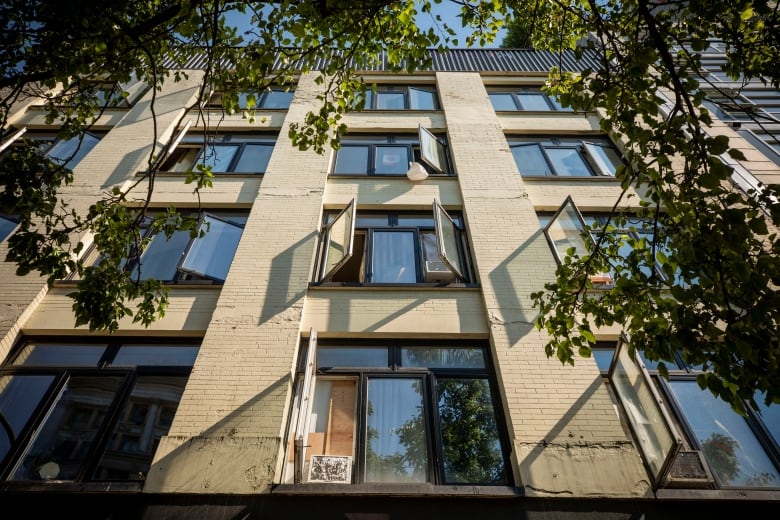 Open windows are seen on an apartment building. 