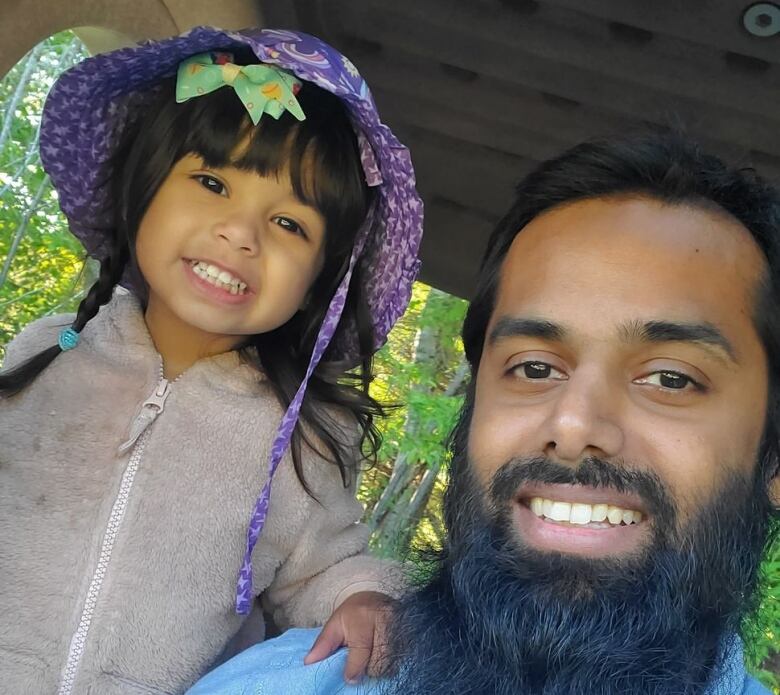 Selfie of a dad and his young daughter smiling at the camera.