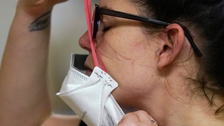 Woman putting on face mask