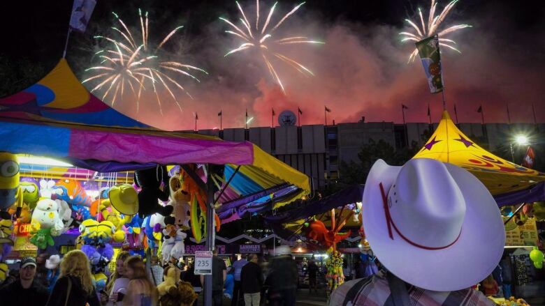 A visitor watches the fireworks display from the midway at the Calgary Stampede in Calgary, Saturday, July 9, 2016. The Stampede, which kicks off with a parade on July 7, is a time when the Calgary-based oilpatch puts on its cowboy boots and hosts pancake breakfasts, beer-soaked barbecues and corporate boxes at the rodeo and chuckwagon races.