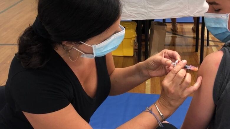 A woman gives a boy a needle in his arm.