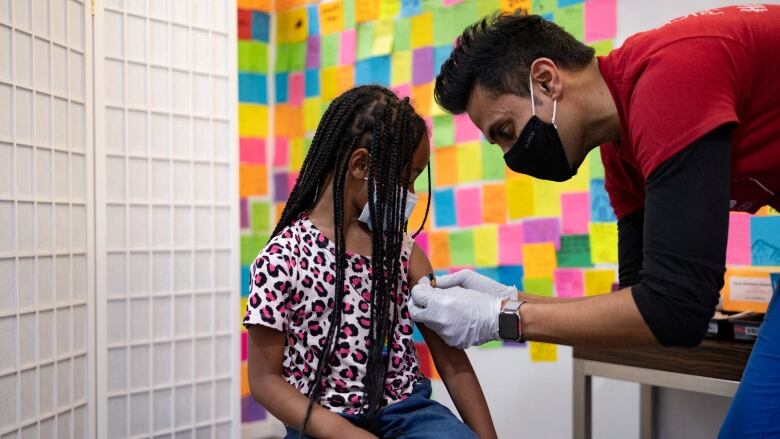 Dr. Mayank Amin puts a band-aid on the arm of five-year-old Lydia Jones after she received a COVID-19 booster vaccine in Schwenksville, Penn. on May 19, 2022. 