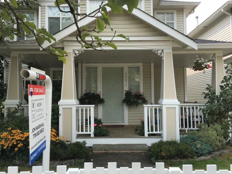 A home featuring lush landscaping with a for sale sign out front.