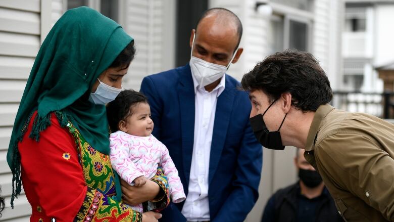 Prime Minister Justin Trudeau gets a smile from Hawa Rahimi, 2 months, as he meets her parents, Obaidullah, right and Arezoo, left, in Ottawa, on Saturday, Oct. 9, 2021. Obaidullah Rahimi worked at the Canadian Embassy in Afghanistan; his family is one of 22 recently resettled Afghan families in the Ottawa area. 