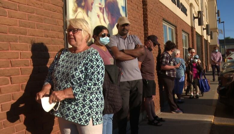 About 10 people lined up outside a building.