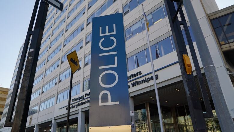 A blue vertical sign reading 'Police' stands in front of a tall office building.