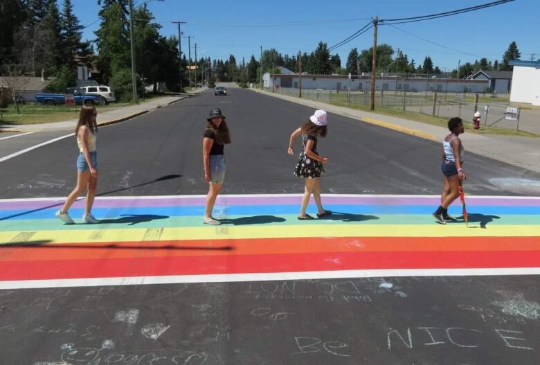 Four young people walk across a rainbow crosswalk in a small Canadian town.