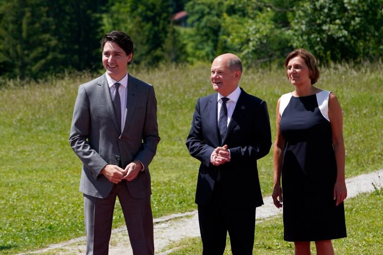 Three politicians pose for photos near a walking trail.