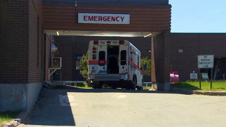 An ambulance parked underneath a sign reading emergency.