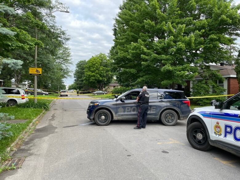 Police watch over a taped-off section of a residential street.