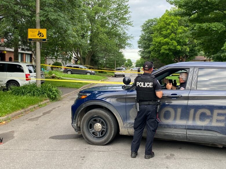 Police watch over a taped-off section of a residential street.