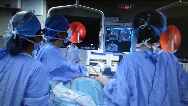 A surgical team surrounds a patient in an operating room.