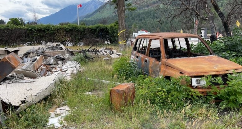 A burnt out car and pile of charred rubble.