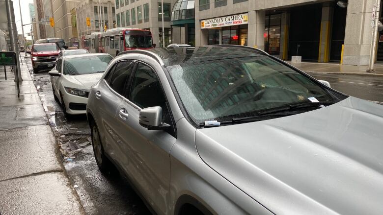 A vehicle with two parking tickets on its dash.