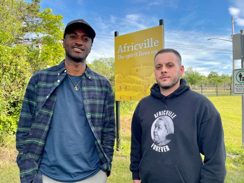 Alfred Burgesson and Edwards Carvery III are seen in front of a sign that reads 