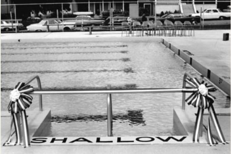 black and white image of a swimming pool shallow end with opening-day ribbons