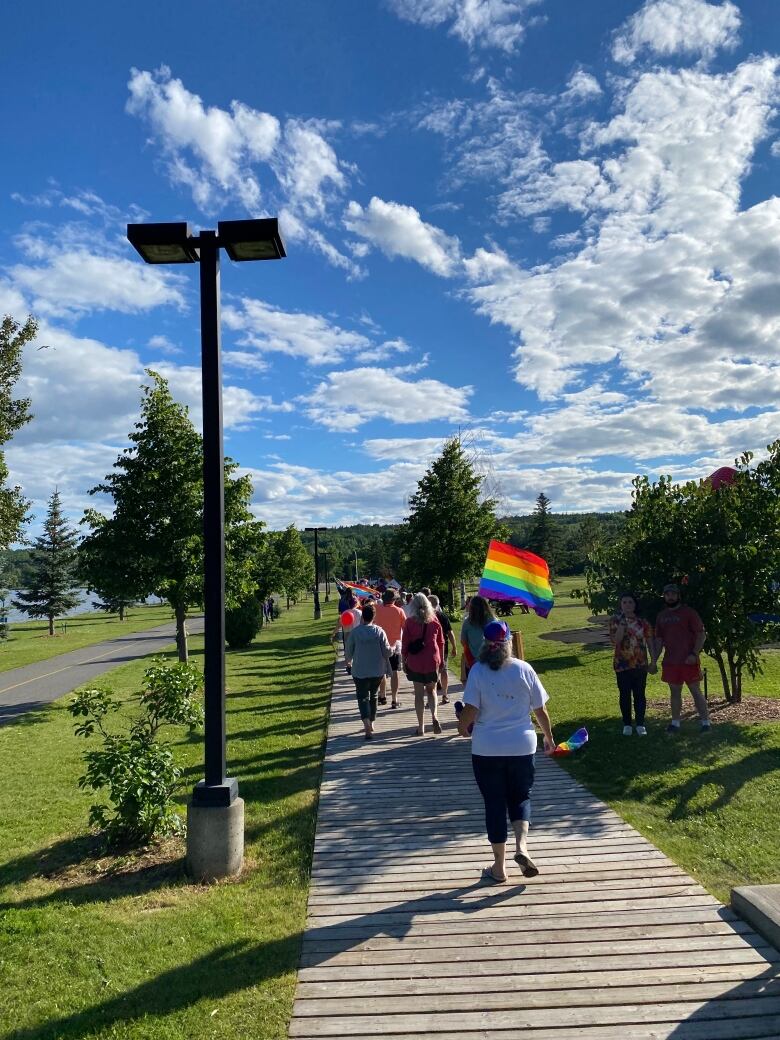 Participants walking along boardwalk holding rainbow flag.