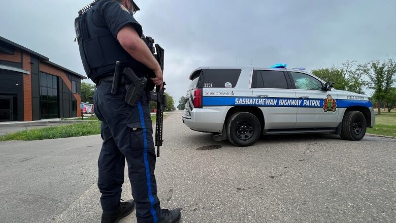 A police officer stands beside a highway patrol vehicle in Langham, Sask.