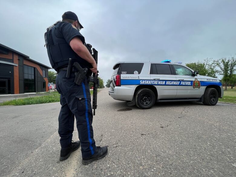 A police officer stands beside a highway patrol vehicle in Langham, Sask.