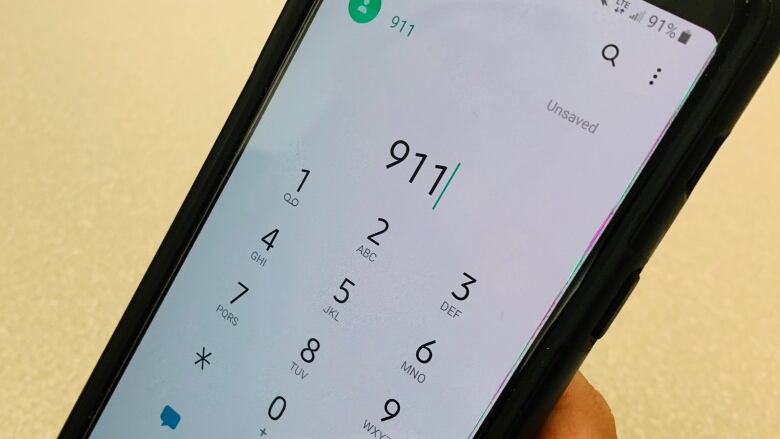 A closeup of a cellphone user dialling 911.