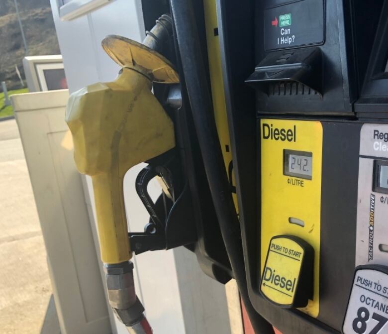 A yellow diesel pump sits in its holder at the gas station.