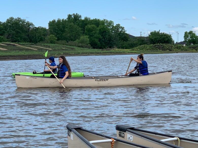 Two people paddle a canoe on a lake.