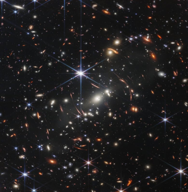 The blackness of space is dotted with bright stars and galaxies.