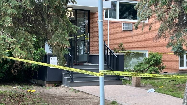 An apartment building is taped off by police as stun guns sit nearby.