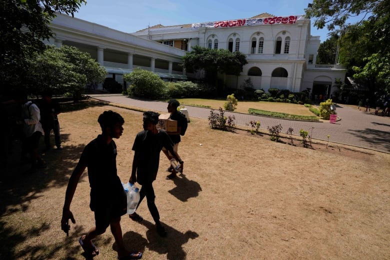 The shadows of several men are seen on the lawn outside a government building.