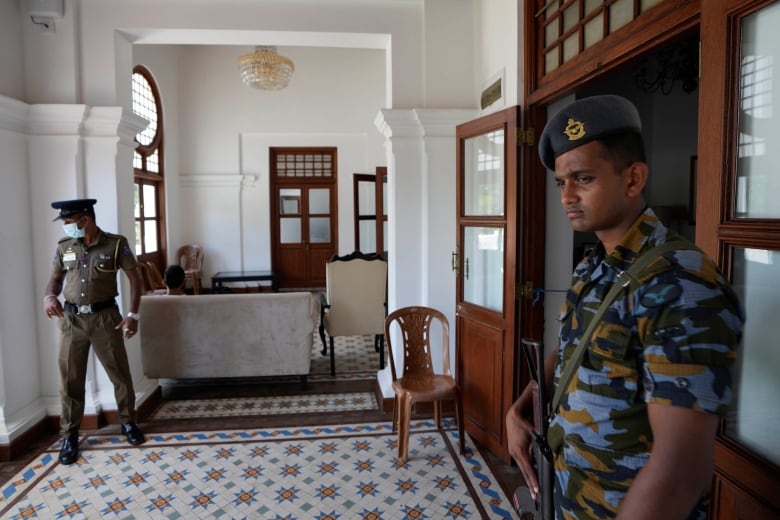 Two men with weapons stand on guard inside a building.