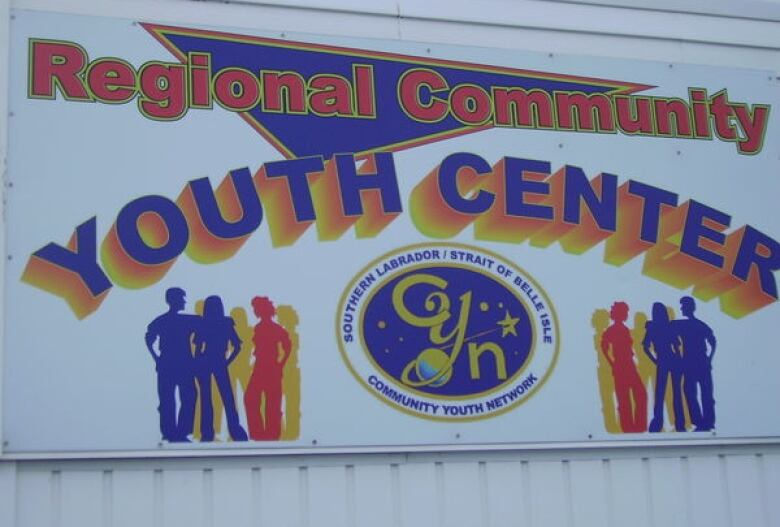 A sign in red and purple lettering that reads Regional Community Youth Centre with silhouettes of people in red and purple. 