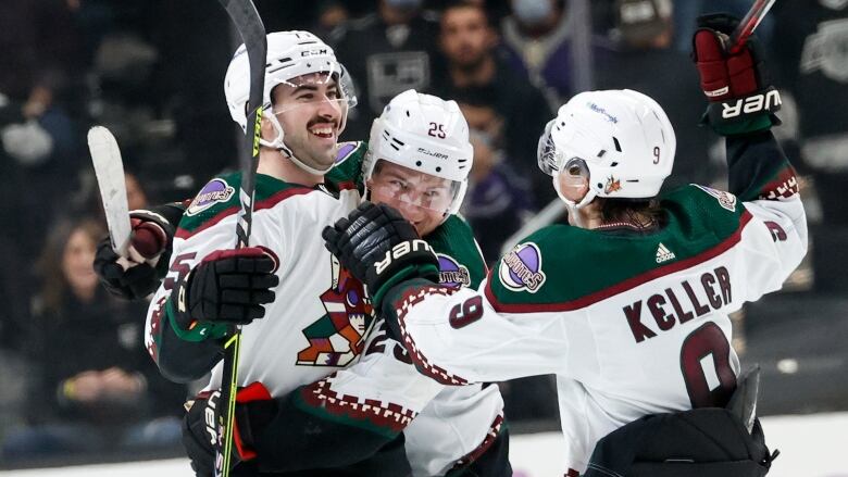 Three hockey players celebrate after a goal.