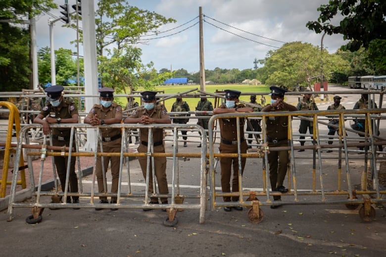 Several men in COVID masks and military fatigues lean against a barricade.