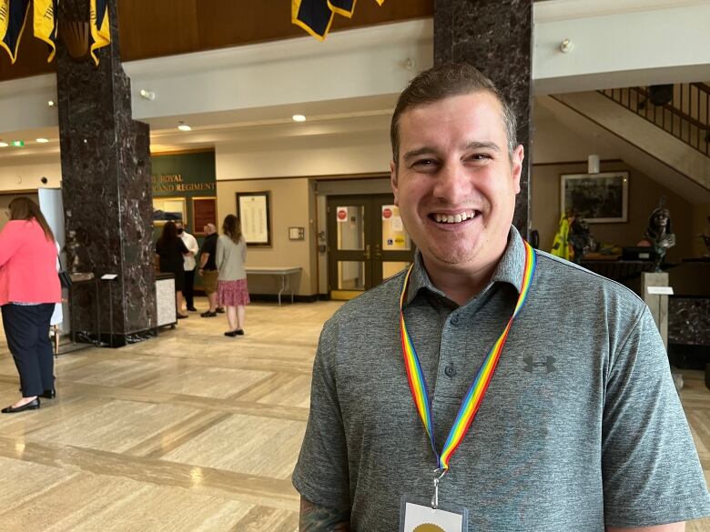 A man wearing a rainbow-coloured lanyard smiles for the camera.