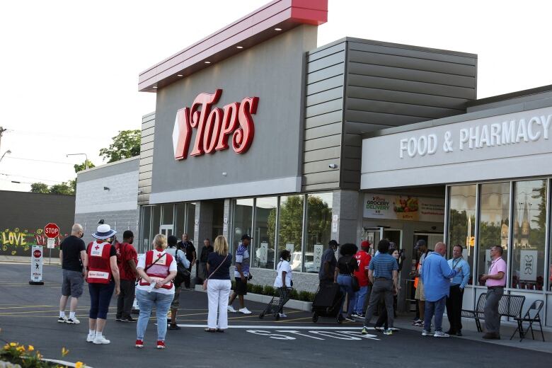 A crowd gathers outside a supermarket.