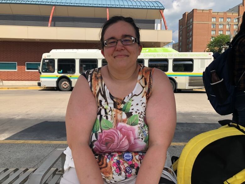 A woman sitting at a bus stop in the extreme heat