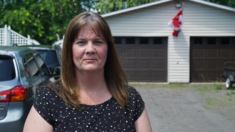 Cathy Deschenes stands in her mother-in-law's suburban Greely driveway in front of the garage where her family sheltered her from the heat during a six-hour wait for an ambulance.