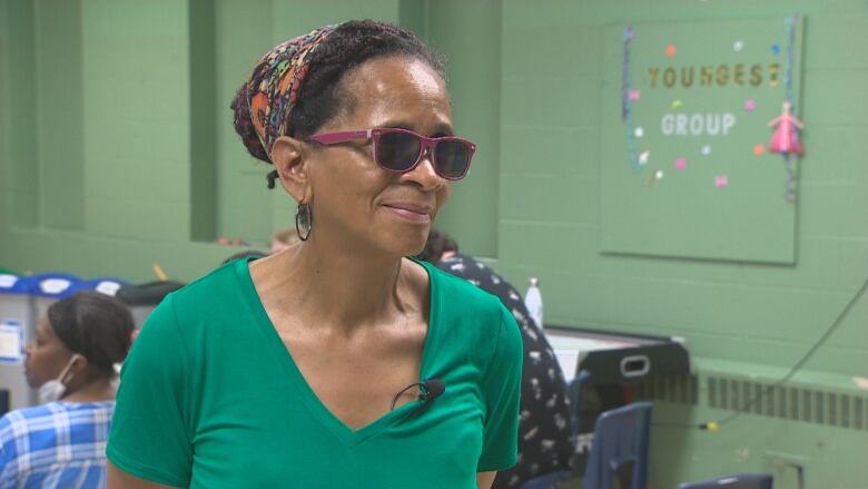 A Black woman wearing sunglasses and a green t shirt