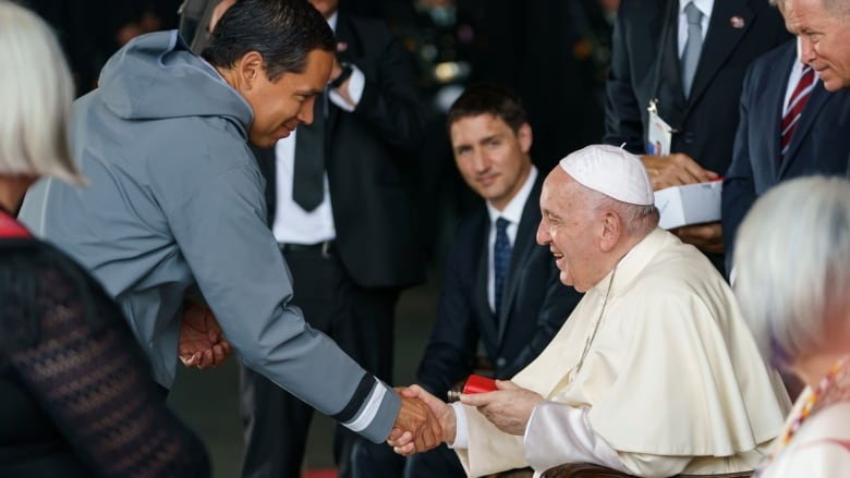 Two men shake hands.