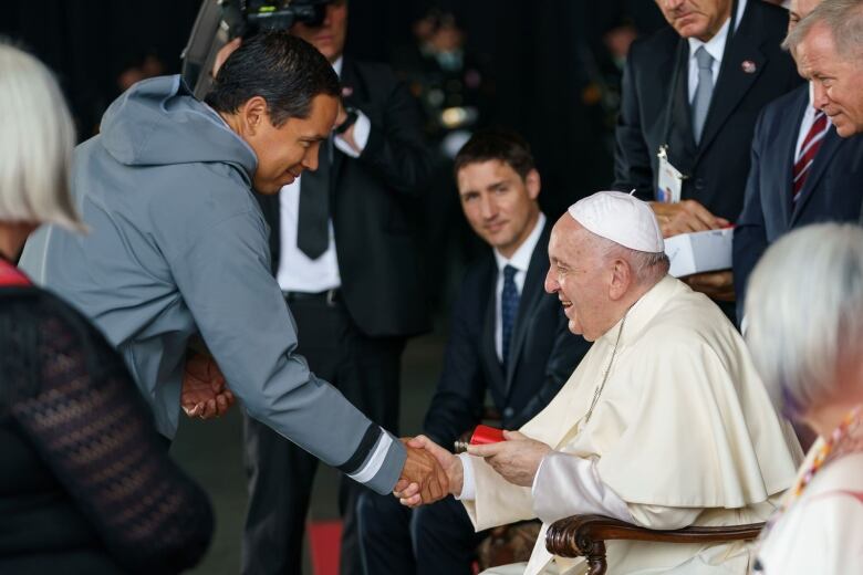 Two men shake hands.