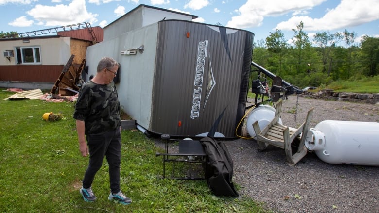 A woman looks at a flipped trailer.