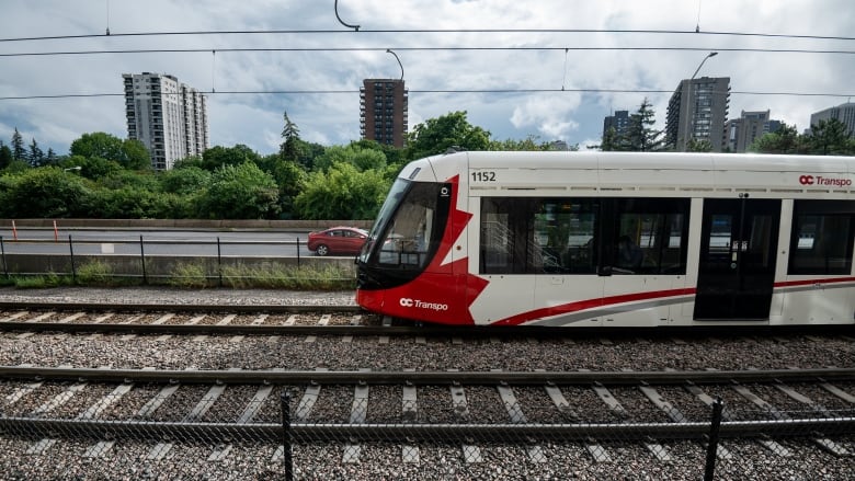 A red and white train moving right to left on tracks.