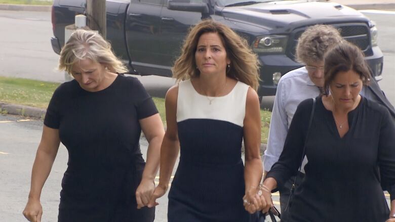 Three women walking hand in hand.