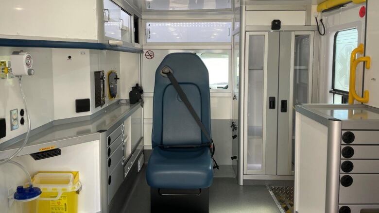 The inside of a new ambulance being leased by the province, showing a single blue chair surrounded by shelves and cabinetry. 