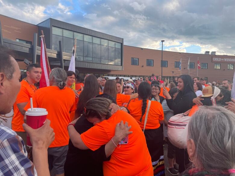 Two people hug in a large crowd. 