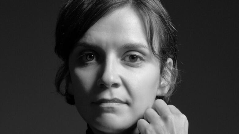 A woman with brown hair tied back in a black and white photo. 