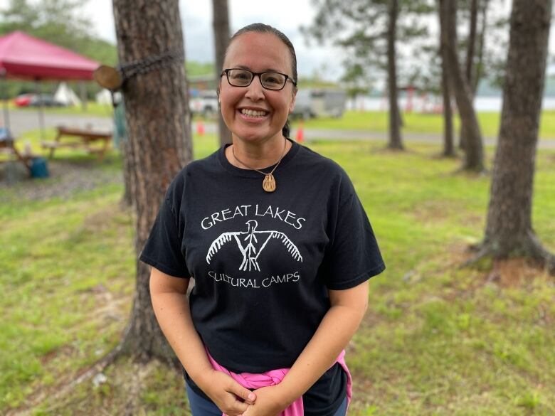 A woman standing outside with a Great Lakes Cultural Camps T-shirt.