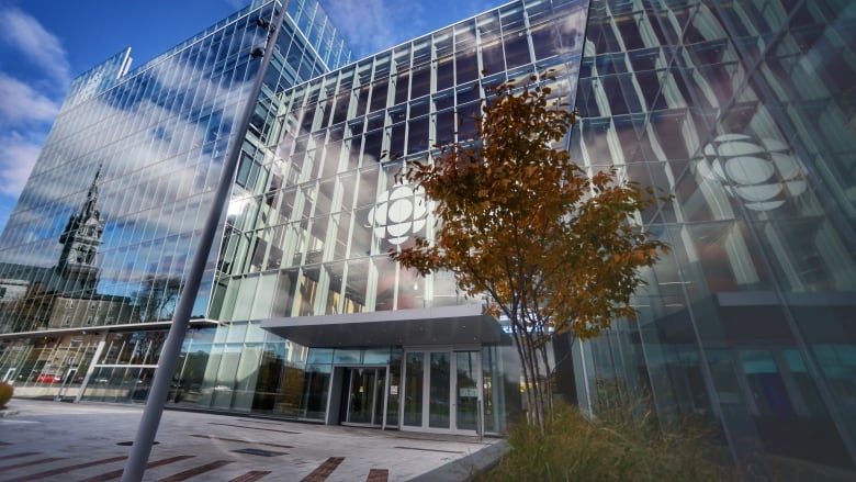 A photograph of the glass facade of the Montreal CBC Building with the logo clearly visible.