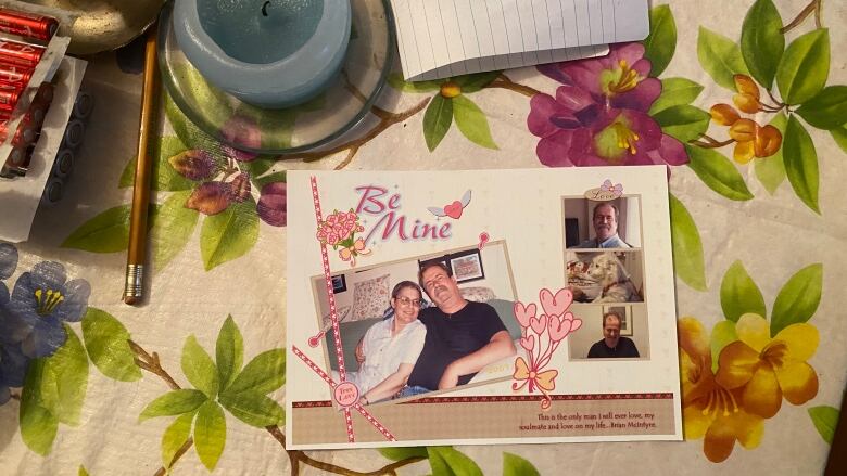 A photo of a man and woman on a table, which has a flower table cloth on it.