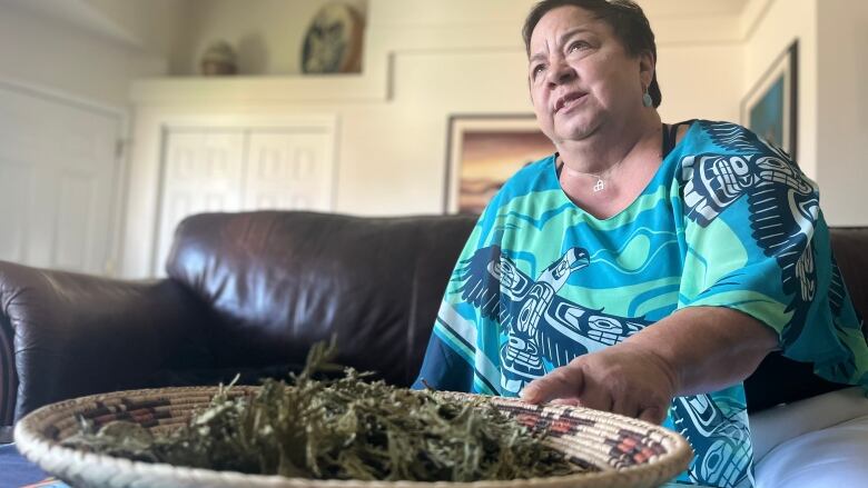 A woman looks up over a bowl of sage.